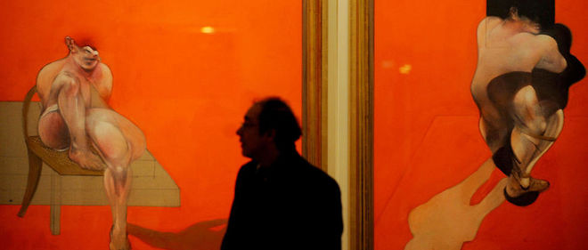 Un homme marchant pres d'un triptyque peint en 1983 par Francis Bacon. Photographie prise lors d'une exposition au Musee du Prado a Madrid en janvier 2009.