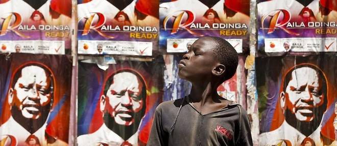 Un jeune garcon kenyan devant les affiches de campagne du candidat de l'opposition Raila Odinga sur le mur pres d'un bureau de vote. 