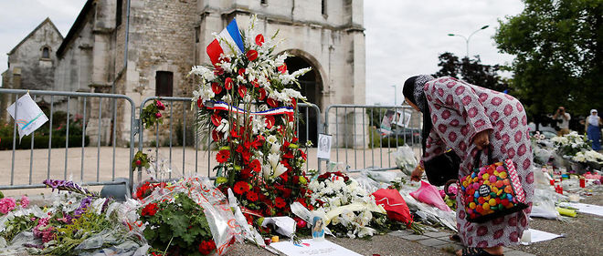 Une femme musulmane depose des fleurs devant l'eglise de Saint-Etienne-du-Rouvray, ou le pere Jacques Hamel a ete egorge le mardi 26 juillet 2016. 