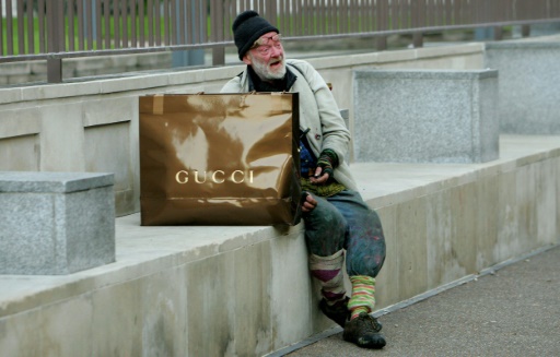 Un sans-abri est assis à côté d'un sac Gucci au centre de Londres, le 15 novembre 2007  © CARL DE SOUZA AFP/Archives