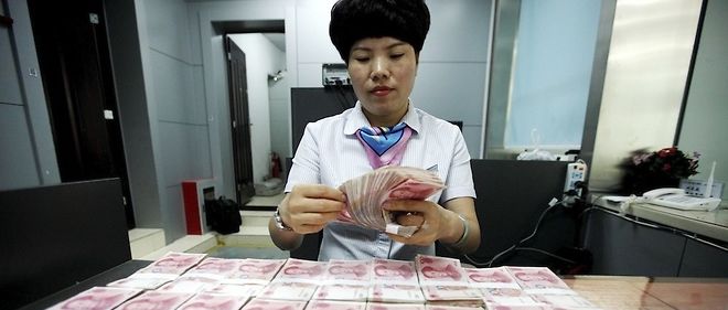 Un employe chinois et des billets de banque a Huaibei, a l'est de la Chine, le 11 aout a 2015.