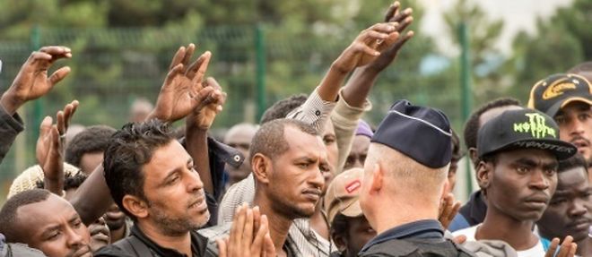 Des migrants de la "jungle" encadres par des policiers attendent un bus a destination d'un centre d'accueil et d'orientation, le 13 septembre 2016 a Calais
