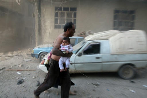Un homme avec un bébé s'enfuit après des bombardements sur Kafr Batna, dans la banlieue de Damas, le 30 septembre 2016 © AMER ALMOHIBANY AFP