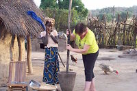 Une touriste s'essaie au maniement du pilon dans un village du Sénégal.