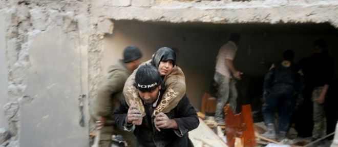 Un secouriste syrien porte une femme sauvee des decombres d'un immeuble apres des bombardements dans le quartier d'al-Hamra a Alep, tenu par les rebelles, le 20 novembre 2016 