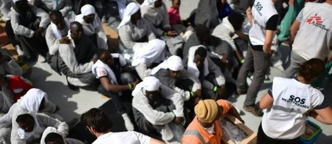 Des membres des ONG Medecins Sans Frontieres et SOS Mediterranee distribuent de la nourriture a des migrants, le 25 mai 2016, au lendemain d'une operation de secours menee par l'Aquarius au large des cotes libyennes