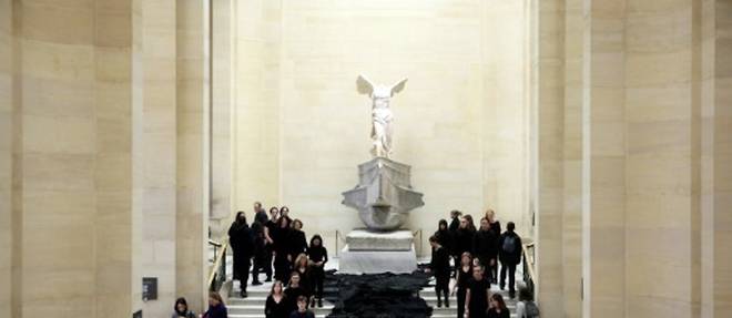Des militants opposes aux energies fossiles deposent des etoffes noires au pied de la Victoire de Samothrace, symbolisant une "riviere de petrole", le 5 mars 2017 au musee du Louvre, a Paris