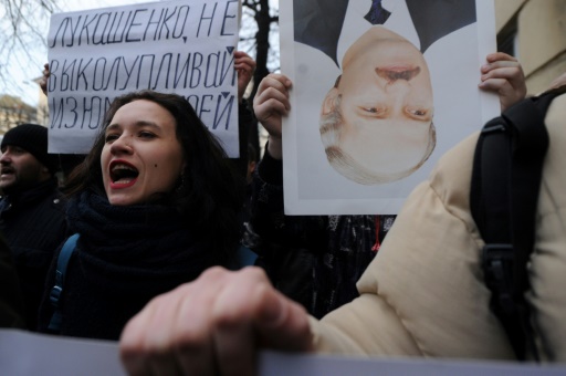 Des opposants brandissent à Minsk, le 15 mars 2017, un portrait tête renversée du président Alexandre Loukachenko, à l'origine d'un projet de taxe contre le "parasitisme social" des gens travaillant moins de six mois par an et suspendu depuis © Sergei Gapon AFP/Archives