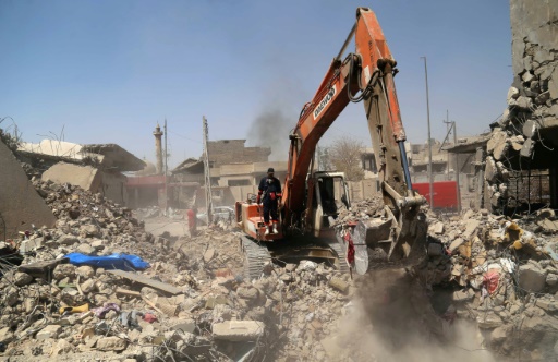 Une pelleteuse de la défense civile creuse dans les décombres de maisons et d'immeubles à la recherche de corps de victimes, le 26 juillet 2017 à Mossoul © SAFIN HAMED AFP