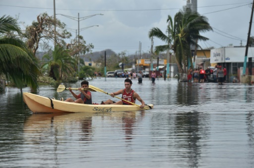 Des habitants utilisent un kayak pour se déplacer dans leur rue inondée, à Juana Matos, sur lîle de Porto Rico, le 21 septembre 2017 après le passage de l'ouragan Maria © HECTOR RETAMAL AFP