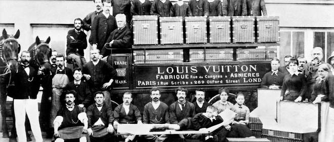 Louis Vuitton (assis sur le siege du conducteur), son fils Georges (a sa droite) et son petit-fils et Gaston-Louis (allonge sur une malle-lit) posent avec les ouvriers a Asnieres vers 1888.