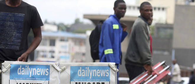 Des passants devant un kiosque a journaux, a Harare, au Zimbabwe, jeudi 16 novembre 2017. 