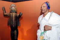  Un souverain du Bénin pose devant la statue de son ancêtre du début du XIXe siècle, lors de sa visite au musée du Quai Branly, en 2007.  