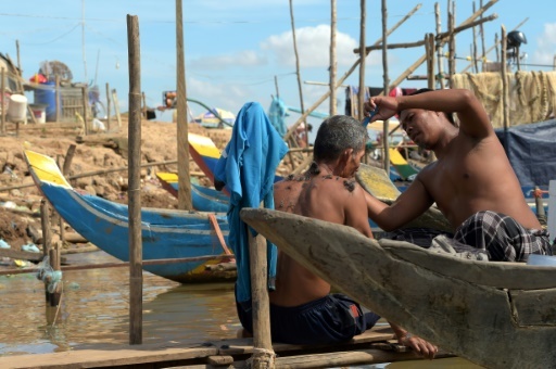 Des pêcheurs cambodgiens en train de se couper les cheveux à bord de leur bateau sur le Mékong, le 5 janvier 2018 © TANG CHHIN SOTHY AFP