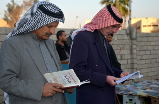 Des Irakiens feuillettent des livres dans une rue de Mossoul (nord), six mois après sa libération des jihadistes, le 12 janvier 2018 © Ahmad MUWAFAQ AFP