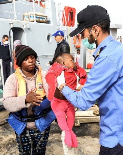 Un enfant secouru au large de la Libye, sur une embarcation de migrants, est débarqué sur la base navale de Tripoli, 10 mars 2018 © MAHMUD TURKIA AFP