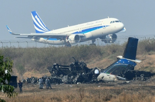 Décollage de l'aéroport international de Katmandou le 13 mars 2018, non loin de l'épave de l'avion de la compagnie bangladaise US-Bangla, qui s'est écrasé lundi à Katmandou faisant 49 morts © PRAKASH MATHEMA AFP