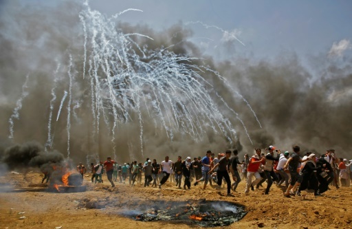 Des manifestants palestiniens courent pour échapper aux gaz lacrymogènes lors d'affrontements avec l'armée israélienne à la frontière entre la bande de Gaza et Israël, le 14 mai 2018 © MOHAMMED ABED AFP