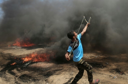 Un Palestinien se sert d'un lance-pierres lors d'affrontements avec l'armée israélienne à la frontière entre la bande de Gaza et l'Etat hébreu, le 14 mai 2018 © SAID KHATIB AFP