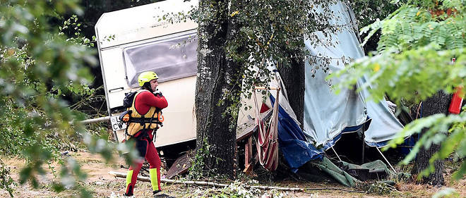 Des sauveteurs marchent pres d'une caravane endommagee par les inondations dues aux orages pres de Saint-Julien-de-Peyrolas le 9 aout.