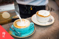 Barista pouring frothy milk into coffee cup, close-up (C)RUSS ROHDE