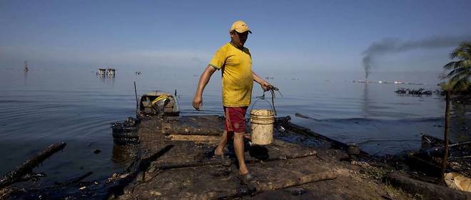 Un pecheur utilise l'eau du lagon de Maracaibo pour laver ses poissons, malgre les fuites de petrole lourd qui les contaminent.