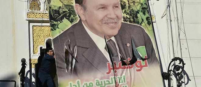 Les manifestants algeriens demolissent un grand panneau publicitaire avec la photo de leur president actuel, Abdelaziz Bouteflika, lors d'une manifestation contre sa candidature pour un cinquieme mandat, le 22 fevrier 2019 a Alger.