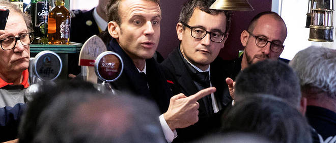 French President Emmanuel Macron (C) flanked by Minister of Public Action and Accounts Gerald Darmanin (2R), meets with locals in a bar where he promised to return during his presidential campaign, in Lens, on November 9, 2018. - Macron is currently on a six-day tour to visit the most iconic landmarks of the First World War ahead of the commemorations of the 100th anniversary of the 11 November 1918 armistice. (Photo by Etienne LAURENT / POOL / AFP)