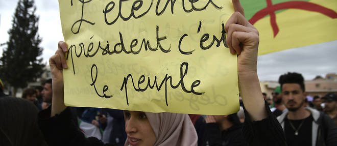 Une manifestante tient une pancarte avec inscrit << l'eternel president, c'est le peuple >>, lors d'une manifestation contre Abdelaziz Bouteflika dans la ville de Bejaia, a quelque 220 kilometres a l'est de la capitale Alger, le 26 mars 2019.