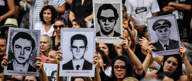 Des manifestants montrent les photos de personnes tuees durant la dictature bresilienne entre 1964 et 1985, dans le parc d'Ibirapuera, a Sao Paulo, le 31 mars 2019.