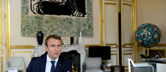Emmanuel Macron repond a une interview du << Point >> dans son bureau. Derriere lui, une tapisserie de  Pierre Alechinsky et, a droite, << Earth Crisis >>, une oeuvre d'Obey. 