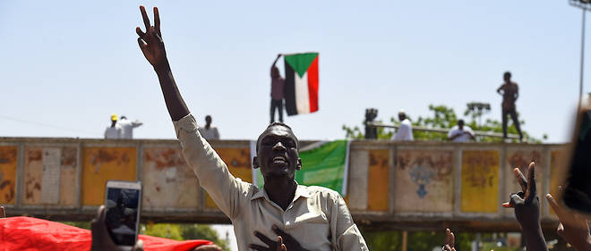 Sudanese protesters wave a national flag near the military headquarters in the capital Khartoum on May 17, 2019, during an ongoing sit-in demanding a civilian-led government transition. - Crowds of Sudanese demonstrators, tore down roadblocks early today on a key avenue in Khartoum, but warned that the barricades will return if the army rulers fail to resume talks over civil rule. (Photo by MOHAMED EL-SHAHED / AFP)