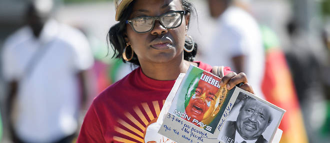 Une femme tient une pancarte lors d'une manifestation avec d'autres << ressortissants camerounais vivant dans differents pays europeens >> contre la presence du president Paul Biya a Geneve le 29 juin 2019.