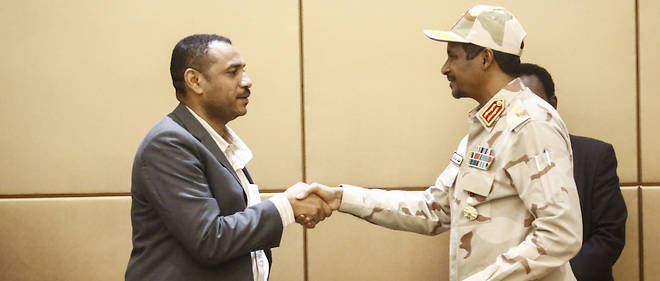 Le general Mohamed Hamdan Daglo (a droite), chef adjoint du Conseil militaire transitoire soudanais, et le chef de la manifestation, Ahmed Rabie, se serrent la main apres avoir signe la declaration constitutionnelle lors d'une ceremonie a laquelle assistaient des mediateurs ethiopiens et de l'Union africaine a Khartoum, la capitale, le 4 aout 2019. 