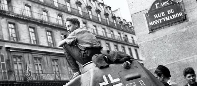 Assis sur un tank allemand, un Gavroche savoure une cigarette en aout 1944.