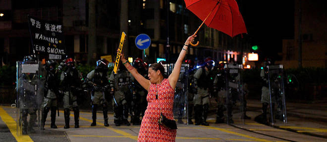Une manifestante se tient avec son parapluie devant des policiers a Hongkong le 1er octobre.