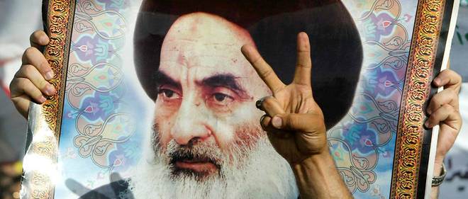 Un manifestant irakien brandit un portrait du Grand ayatollah Ali Sistani lors d'un rassemblement en 2004. 
