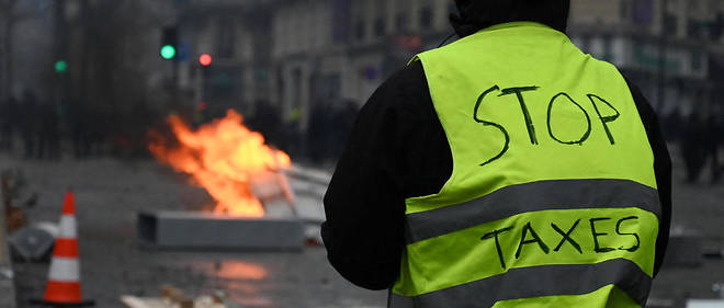 Un manifestant avec ecrit stop taxes sur son gilet jaune. Les Gilets jaunes s'insurgent dans Paris pour l'episode 3. 