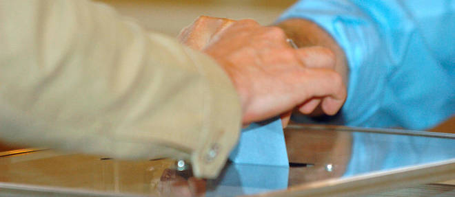 Photo d'une urne ou une personne depose un bulletin de vote.
