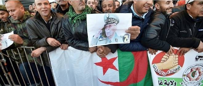 Une photo du general Gaid Salah dans les mains de la foule au bord de la route des funerailles de l'ex-homme fort de l'Algerie.
