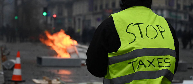 Un manifestant avec ecrit stop taxes sur son gilet jaune. Les Gilets jaunes s'insurgent dans Paris pour l'episode 3. 