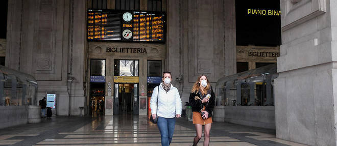 Des gens portant des masques a la gare de Milan.
