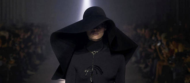 Une grande capeline noire et un collier au pendentif oversize accompagnent le premier look du defile Givenchy.
