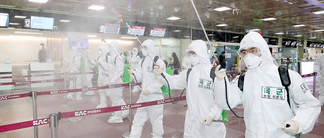 Des militaires sud-coreens equipes de combinaisons de protection repandent du desinfectant dans l'aeroport de Daegu le 6 mars. 
