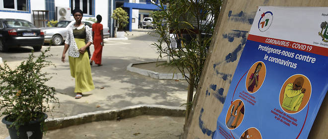 Des passants sont sensibilises au coronavirus par le biais d'affiches. Ici, elles sont placardees dans la cour d'une eglise fermee  a Abidjan le 20 mars 2020.
