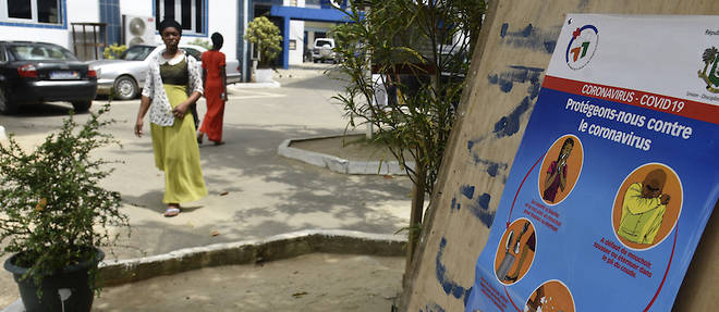 Des passants sont sensibilises au coronavirus par le biais d'affiches. Ici, elles sont placardees dans la cour d'une eglise fermee  a Abidjan le 20 mars 2020.

