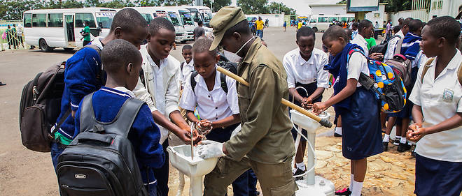 Les eleves du secondaire au Rwanda se lavent les mains au point de lavage temporaire avant de rentrer chez eux apres que les autorites ont ferme tous les internats.
