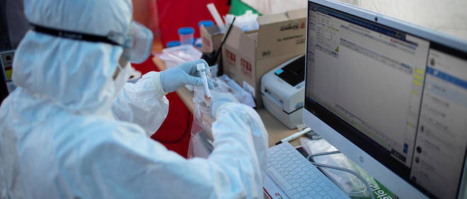 Une infirmiere place un test de Covid-19 dans un sachet plastique afin de l'envoyer pour analyse au centre hospitalier Yang Ji a Seoul en Coree du Sud le 26 mars 2020. 
