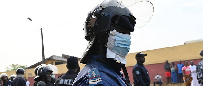 Un officier de police anti-emeute de la Cote d'Ivoire porte un masque facial lors d'affrontements avec des residents lors d'une manifestation contre la construction d'un centre de depistage du Covid-19 dans le quartier de Yopougon en debut de semaine.  

