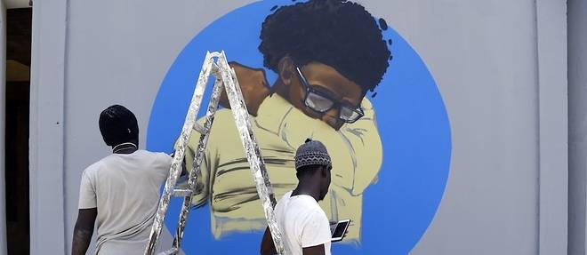 Les membres du collectif graffitti senegalais RBS CREW tagguent un mur du Centre des Oeuvres Universitaires (COUD) de l'universite Cheikh-Anta-Diop a Dakar avec un graffitti representant un homme eternuant dans son coude, a titre preventif contre le coronavirus Covid-19.
